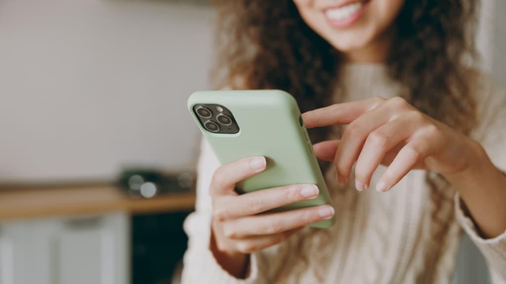 Cropped young smiling woman using mobile cell phone