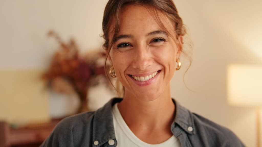 A warm, friendly portrait of a smiling woman in a casual denim shirt.