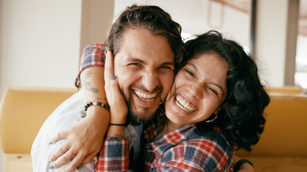 Joyful couple hugging, making silly faces and laughing together