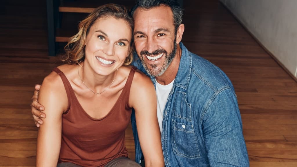 Mature couple, happy and hugging at home on floor.