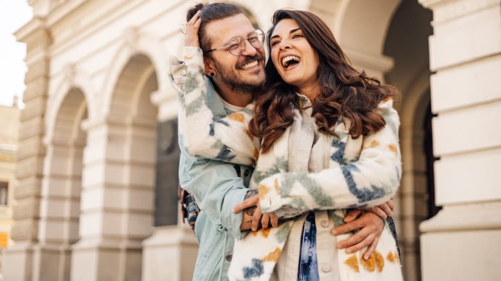 Portrait of happy alternative hipster couple in love standing on city street