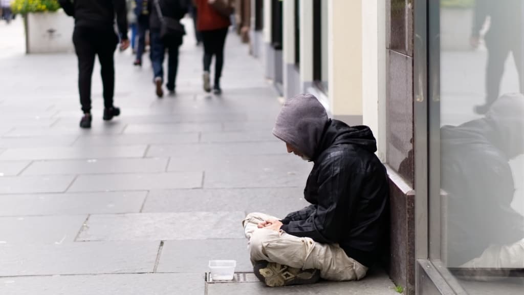 Homeless man sitting on the pavement