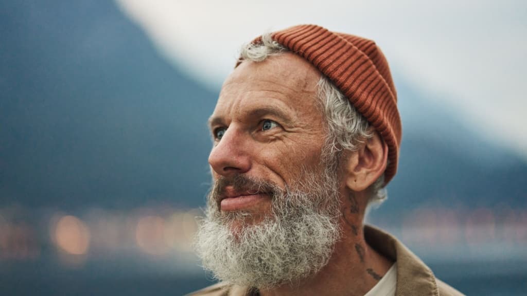 Happy older bearded man standing in nature park enjoying landscape.