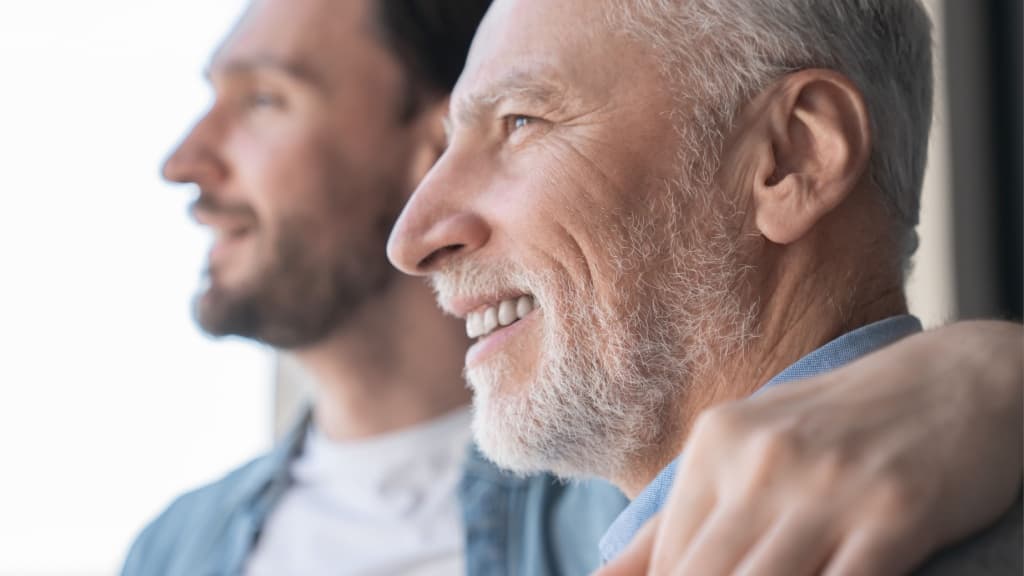 Close up shot of a caucasian young adult son supporting his old elderly senior man looking at the window