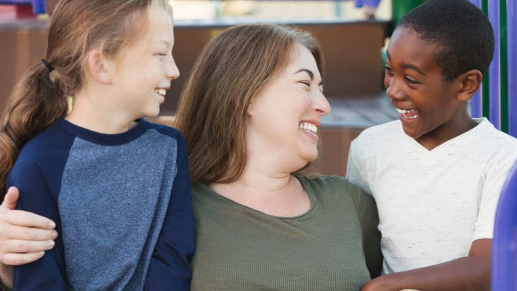 Woman comforting two young children.