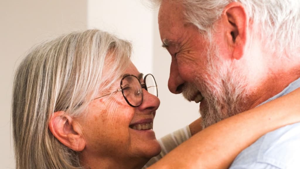 Close-up of a happy elderly couple embracing joyfully at home