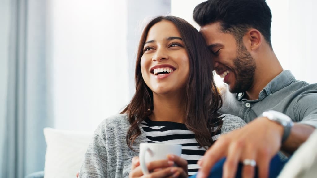 Couple laughing and cuddling on the sofa.