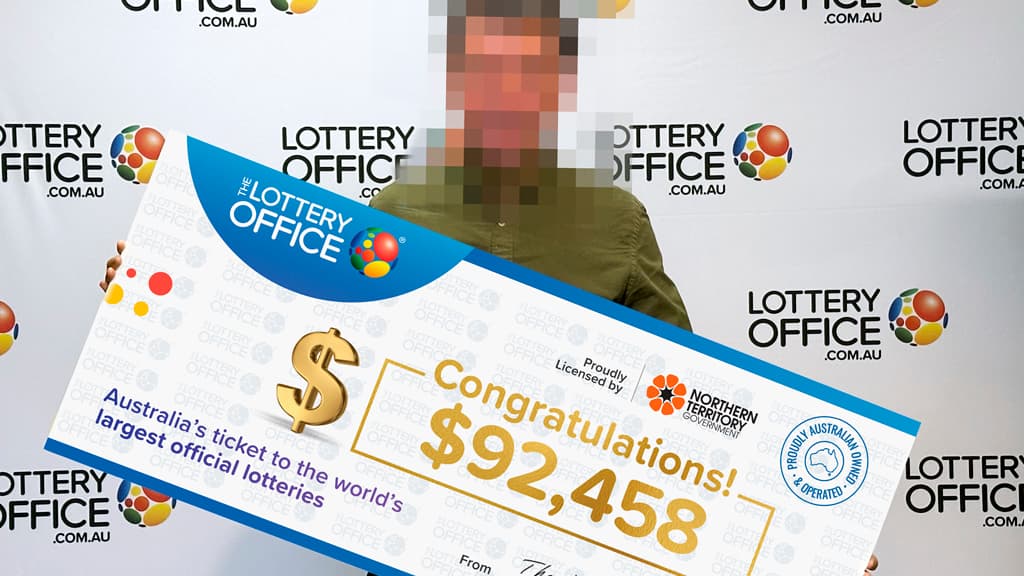 Man with face blurred holding a cheque.